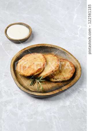 Delicious golden potato cakes served on a rustic wooden plate with dipping sauce Delicious golden potato cakes served on a rustic wooden plate with dipping sauce 122561185