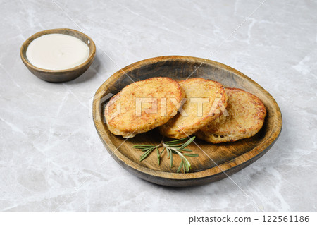 Delicious homemade potato pancakes served with creamy dip on a rustic wooden plate Delicious homemade potato pancakes served with creamy dip on a rustic wooden plate 122561186