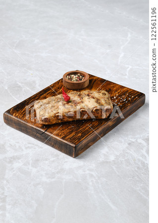 Grilled pork ribs on a rustic wooden board, with a small bowl of mixed spices 122561196
