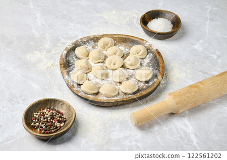 Homemade dumplings prepared on a wooden plate with spices and flour on a kitchen countertop Homemade dumplings prepared on a wooden plate with spices and flour on a kitchen countertop 122561202