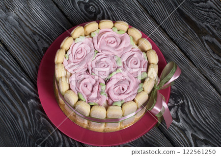 Cake with Savoiardi cookies and marshmallow roses. Tied with ribbon. The ribbon is tied into a bow. 122561250