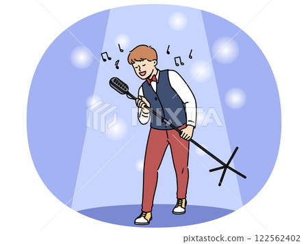 Talented boy singer holds professional microphone on tripod standing in light of spotlight 122562402