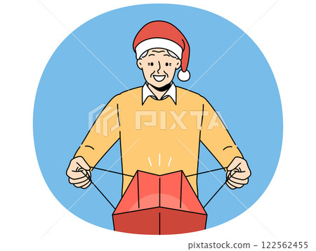 Elderly man in santa claus hat opens package with christmas gift and joy at receiving present Elderly man in santa claus hat opens package with christmas gift and joy at receiving present 122562455