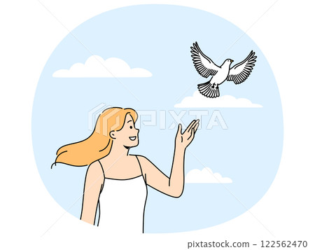 Woman releases dove standing under summer blue sky and watching bird symbolize hope and peace 122562470