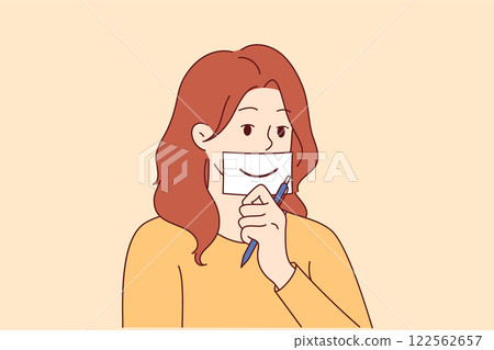 Woman shows fake smile, symbolizing happiness, by placing piece of paper with drawn mouth on face 122562657