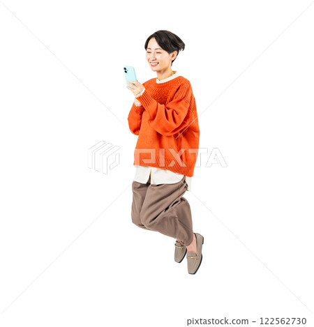 A stylish middle-aged woman jumping while looking at her smartphone. A transparent full-body photo PNG precisely cut by hand 122562730