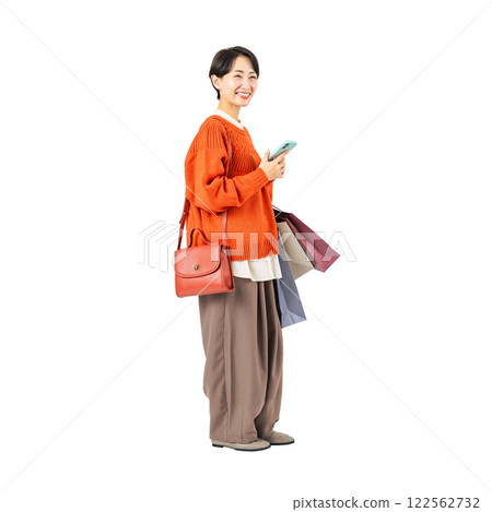 Middle-aged woman using a smartphone while holding a shopping bag. Full-body photo PNG with transparent background precisely cut by hand 122562732