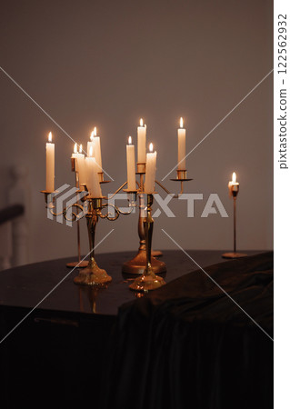 Burning candles in metal candlesticks on the table Burning candles in metal candlesticks on the table 122562932