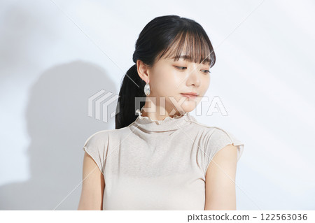 A refreshing beauty portrait of a young woman photographed against a light and shadow background A refreshing beauty portrait of a young woman photographed against a light and shadow background 122563036