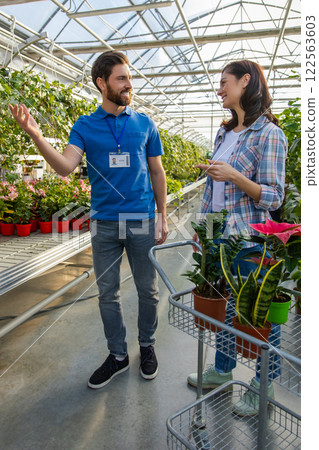 Salesman at retail store offering potted plants and flowers to woman customer Salesman at retail store offering potted plants and flowers to woman customer 122563603