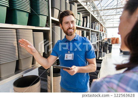 Bearded man worker assisting woman customer with purchasing products for flowers cultivating in retail market 122563628