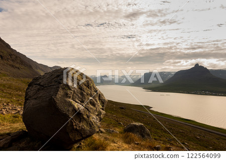 A large rock sits atop a hill overlooking a Fjord in the westfjords. Iceland 122564099