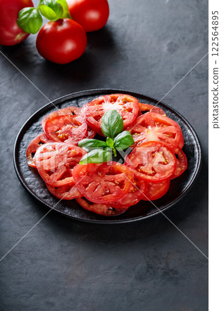 Red Tomato Slices and Basil Leaves on Black Plate, Mediterranean Cuisine 122564895