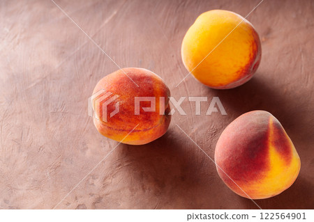 Three Ripe Peaches on Brown Clay Background, Copy Space Three Ripe Peaches on Brown Clay Background, Copy Space 122564901