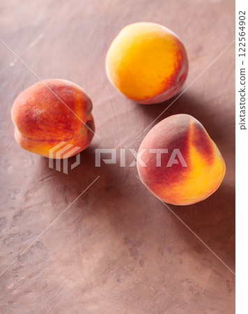 Three Ripe Peaches on Brown Clay Background, Copy Space 122564902