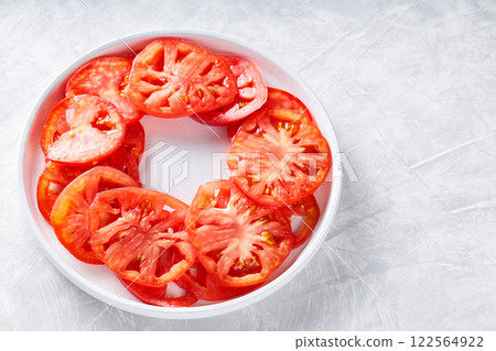 Fresh Tomato Slices Arranged in Circle on White Plate, Light Grey Textured Background, Top View, Copy Space 122564922