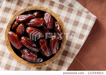 Dried Dates in Wooden Bowl on Beige Checkered Napkin 122564923