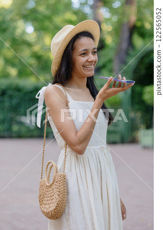 African American woman in white dress records audio message on smartphone. adorable female model African American woman in white dress records audio message on smartphone. adorable female model 122565052