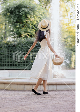 view from back. Happy African American woman in white dress and straw hat and bag, posing view from back. Happy African American woman in white dress and straw hat and bag, posing 122565055