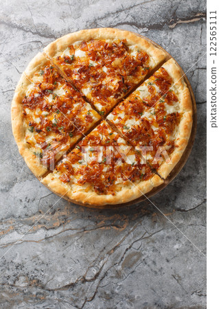 Caramelized onion pizza in French onion soup style with gruyere cheese and mozzarella close-up on wooden board. Vertical top view 122565111