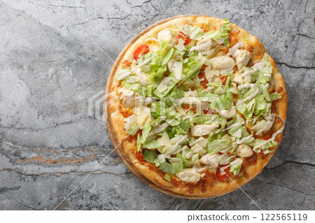 Homemade Caesar pizza with delicate sauce, cheese, tomatoes, chicken breast and lettuce close-up on a wooden board. horizontal top view 122565119