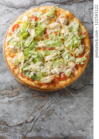 Delicious pizza Caesar salad with chicken, parmesan,, cherry tomatoes and fresh lettuce closeup on the wooden board. Vertical top view 122565122