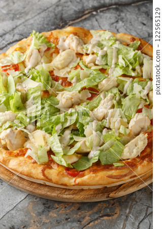 Delicious pizza Caesar salad with chicken, parmesan,, cherry tomatoes and fresh lettuce closeup on the wooden board. Vertical 122565129