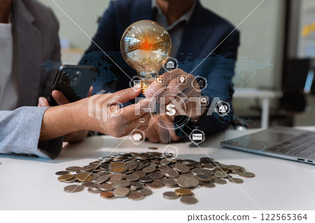 businessman hand holding lightbulb with using laptop computer and money stack in office. idea saving energy and accounting finance concept in office. businessman hand holding lightbulb with using laptop computer and money stack in office. idea saving energy and accounting finance concept in office. 122565364