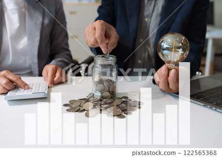 businessman hand holding lightbulb with using laptop computer and money stack in office. idea saving energy and accounting finance concept in office. businessman hand holding lightbulb with using laptop computer and money stack in office. idea saving energy and accounting finance concept in office. 122565368