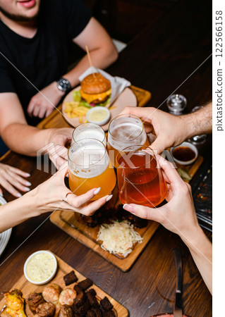 Friends toasting with beer over dinner table. 122566158