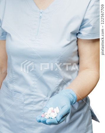 Hand of a female doctor in a blue glove with pile of pills. Hand of a female doctor in a blue glove with pile of pills. 122567709