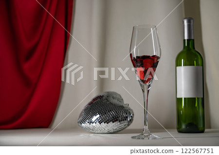 Wine glass with heart confetti, bottle, and disco on cream background. Minimalist holiday photo for Valentines lowkey 122567751