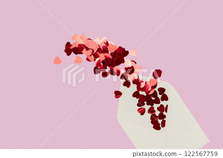 Creative minimalist composition of cream letter envelope spilling heart-shaped confetti, set against a pink background, symbolizing love and warmth. Creative minimalist composition of cream letter envelope spilling heart-shaped confetti, set against a pink background, symbolizing love and warmth. 122567759