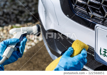 A man washing his car in his home parking lot 122568851