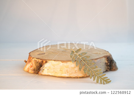 A pedestal made of birch sawn wood for advertising a product with twigs and leaves. Minimalistic creative composite background for the presentation of cosmetics or products. Front view 122568912
