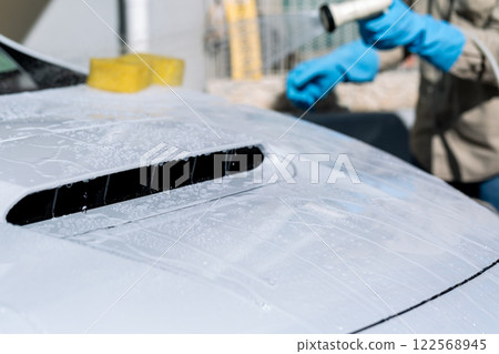 A man washing his car in his home parking lot A man washing his car in his home parking lot 122568945