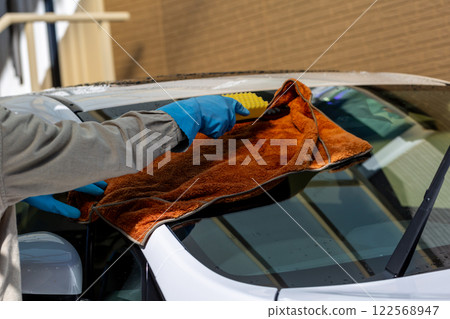 A man washing his car in his home parking lot 122568947