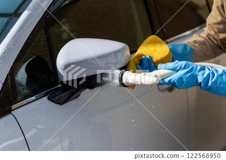 A man washing his car in his home parking lot A man washing his car in his home parking lot 122568950