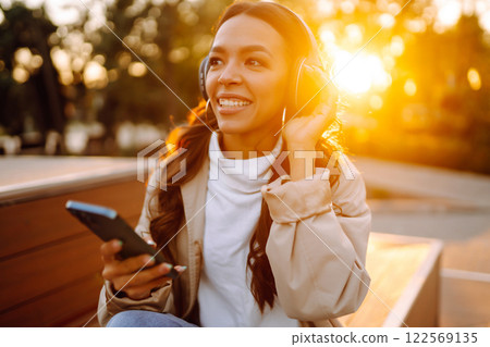 Young woman listens to music, audiobook or podcast. Communication in social networks. Lifestyle. 122569135