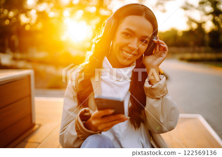 Young woman listens to music, audiobook or podcast. Communication in social networks. Lifestyle. 122569136