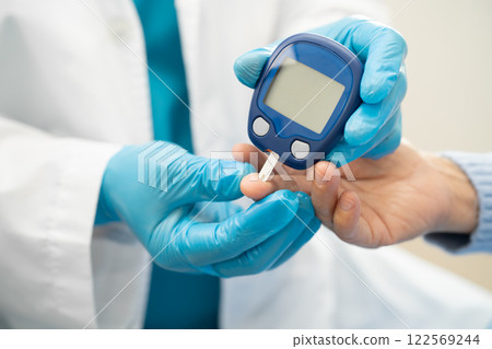 Doctor check diabetes from finger blood sugar level with finger lancet. 122569244