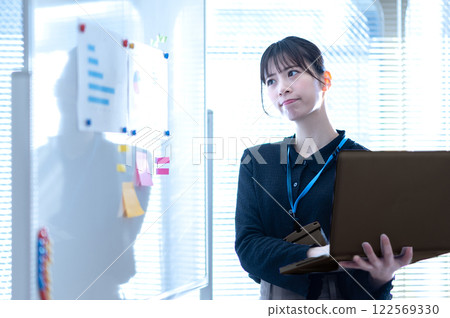 A young businesswoman thinking about the content of a presentation in front of a whiteboard 122569330