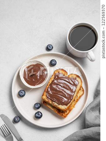 Toasted bread with chocolate cream on  a plate on a light  background with a cup of espresso coffee 122569370