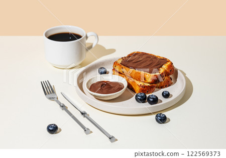 Toasted bread with chocolate cream on a plate with blueberry on a light  background 122569373