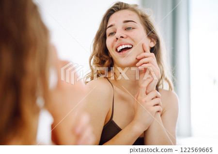 Beautiful woman with acne problem skin checks dry face skin. Red spots, rash, acne. Skin treatment. 122569665