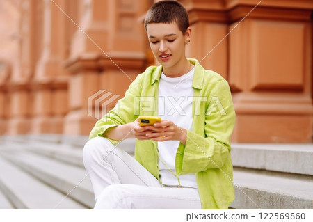 Portrait of woman with short haircut posing on city streets, with phone. Technology, style concept. Portrait of woman with short haircut posing on city streets, with phone. Technology, style concept. 122569860