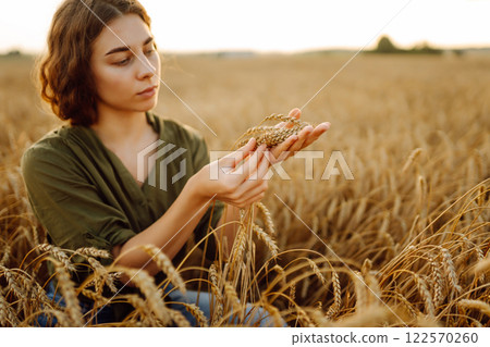 Woman farmer analyzes the harvest in a golden wheat field. Agronomist checks the progress of harvest 122570260
