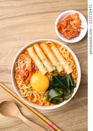 Spicy noodles soup with Tteokbokki, Wakame seaweed and fresh egg yok eating with kimchi cabbage 122570471