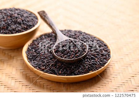 Organic rice berry or purple rice on wooden plate with spoon, Thai rice Organic rice berry or purple rice on wooden plate with spoon, Thai rice 122570475