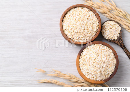 Oat flakes in wooden bowl and spoon on white background with copy space Oat flakes in wooden bowl and spoon on white background with copy space 122570506